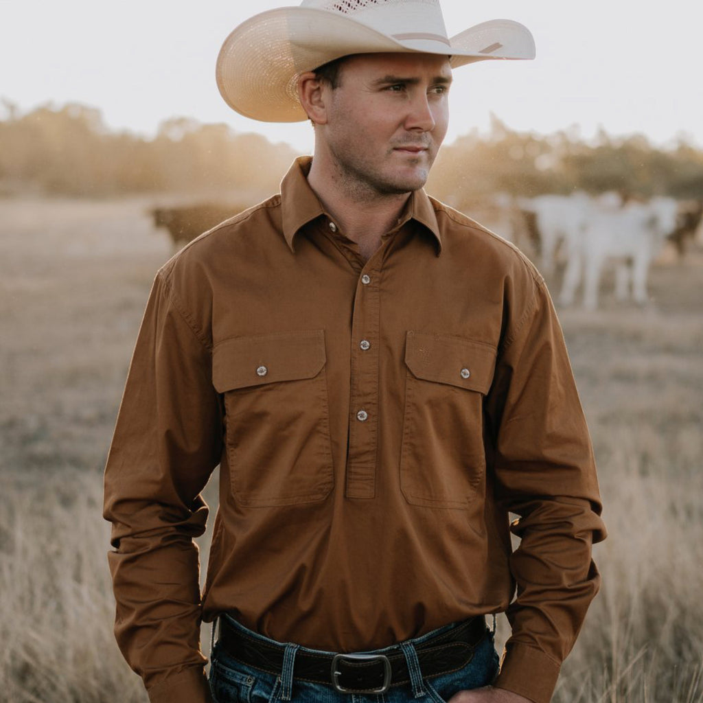 Man wearing a brown shirt and cowboy hat in a field